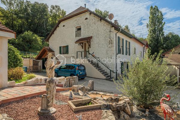 Sur la commune de Seyssel, à moins de 2 kilomètres du centre-ville et de toutes les commodités, venez découvrir cette jolie maison mitoyenne sans vis à vis de 136 m², bénéficiant d’un environnement agréable et d’un vaste terrain arboré de 2 792 m².

La maison se compose d’une cuisine ouverte sur le séjour avec accès direct à une première grande terrasse. Une suite parentale complète ce niveau avec chambre, salle d’eau, WC et accès à une seconde terrasse indépendante.

À l’étage, vous découvrirez un grand salon, trois chambres ainsi qu’une salle de bains avec WC. Les combles, déjà accessibles par un escalier, offrent un potentiel d’aménagement supplémentaire.

L’extérieur constitue un véritable atout de cette propriété. Le grand terrain, arboré et soigneusement entretenu, offre de nombreuses possibilités d’aménagement selon vos envies. Vous profiterez d’un espace potager/jardin, de deux terrasses extérieures, d’un grand espace de stationnement ainsi que d’un portail permettant de sécuriser l’accès à la propriété.

Le jardin bénéficie également d’une belle vue sur le Grand Colombier, apportant un cadre particulièrement agréable aux espaces extérieurs. Un atelier vient compléter l’ensemble.

Une maison pleine de charme, à découvrir sans tarder.