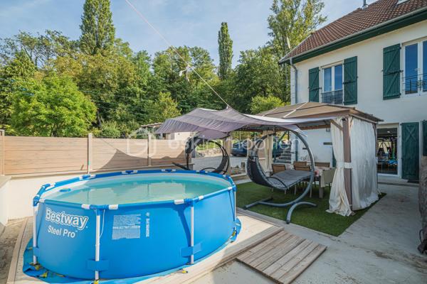 Sur la commune de Seyssel, à moins de 2 kilomètres du centre-ville et de toutes les commodités, venez découvrir cette jolie maison mitoyenne sans vis à vis de 136 m², bénéficiant d’un environnement agréable et d’un vaste terrain arboré de 2 792 m².

La maison se compose d’une cuisine ouverte sur le séjour avec accès direct à une première grande terrasse. Une suite parentale complète ce niveau avec chambre, salle d’eau, WC et accès à une seconde terrasse indépendante.

À l’étage, vous découvrirez un grand salon, trois chambres ainsi qu’une salle de bains avec WC. Les combles, déjà accessibles par un escalier, offrent un potentiel d’aménagement supplémentaire.

L’extérieur constitue un véritable atout de cette propriété. Le grand terrain, arboré et soigneusement entretenu, offre de nombreuses possibilités d’aménagement selon vos envies. Vous profiterez d’un espace potager/jardin, de deux terrasses extérieures, d’un grand espace de stationnement ainsi que d’un portail permettant de sécuriser l’accès à la propriété.

Le jardin bénéficie également d’une belle vue sur le Grand Colombier, apportant un cadre particulièrement agréable aux espaces extérieurs. Un atelier vient compléter l’ensemble.

Une maison pleine de charme, à découvrir sans tarder.