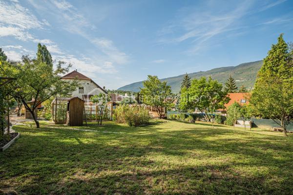 Sur la commune de Seyssel, à moins de 2 kilomètres du centre-ville et de toutes les commodités, venez découvrir cette jolie maison mitoyenne sans vis à vis de 136 m², bénéficiant d’un environnement agréable et d’un vaste terrain arboré de 2 792 m².

La maison se compose d’une cuisine ouverte sur le séjour avec accès direct à une première grande terrasse. Une suite parentale complète ce niveau avec chambre, salle d’eau, WC et accès à une seconde terrasse indépendante.

À l’étage, vous découvrirez un grand salon, trois chambres ainsi qu’une salle de bains avec WC. Les combles, déjà accessibles par un escalier, offrent un potentiel d’aménagement supplémentaire.

L’extérieur constitue un véritable atout de cette propriété. Le grand terrain, arboré et soigneusement entretenu, offre de nombreuses possibilités d’aménagement selon vos envies. Vous profiterez d’un espace potager/jardin, de deux terrasses extérieures, d’un grand espace de stationnement ainsi que d’un portail permettant de sécuriser l’accès à la propriété.

Le jardin bénéficie également d’une belle vue sur le Grand Colombier, apportant un cadre particulièrement agréable aux espaces extérieurs. Un atelier vient compléter l’ensemble.

Une maison pleine de charme, à découvrir sans tarder.