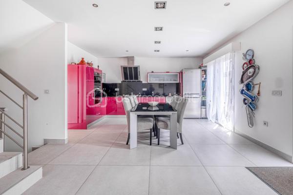 Élevée et baignée de lumière, cette maison de 124 m² de surface habitable, offrant 175 m² de surface utile au total avec buanderie et garage, récente offre une vraie vie de famille chic et pratique, à deux pas des commodités de Champigny.

Les atouts qui font la différence

Entrée majestueuse: on gravit quelques marches et l’on découvre un grand séjour traversant, chaleureux, ouvert sur la terrasse surélevée – parfait pour recevoir.
Cuisine esprit « family room »: moderne, entièrement équipée, conviviale autour de la table centrale.
Salon cocooning avec cheminée: belles soirées assurées hiver comme été.

Rez‑de‑jardin polyvalent

- Chambre indépendante parfaite pour télétravail, ado ou invités.
- Couloir avec rangements intégrés très pratiques.
-  Salle d’eau avec douche et WC.
- Buanderie attenante.
- Grand garage motorisé + portail électrique, borne de recharge pour véhicule électrique.

Étage nuit

- Deux chambres confortables avec rangements, traversantes, équipées de Velux et volets roulants électriques pour une lumière maîtrisée et un confort optimal.
- Spacieuse salle de bains: baignoire, douche, double vasque.
- WC séparés.

Confort et équipements

- Jardin paysager, impeccablement entretenu, sans vis‑à‑vis: véritable prolongement du séjour pour des réceptions élégantes.
 - Espace latéral prêt à vivre (eau + électricité): parfait pour imaginer une cuisine d’été raffinée, un jacuzzi ou un lounge extérieur.
- Fermetures premium: volets roulants électriques sur baies et Velux, double vitrage performant, éclairages encastrés.
- Stationnement d’exception: double garage fermé avec porte motorisée, portail d’entrée électrique pour un accès fluide et sécurisé.
- Mobilité de demain: borne de recharge pour véhicule électrique intégrée.
- Praticité quotidienne: buanderie dédiée, rangements généreux, matériaux choisis pour leur durabilité et leur facilité d’entretien.
- Chauffage performant: chaudière gaz à condensation Frisquet avec plancher chauffant, complétée par un insert bois pour l’appoint; production d’eau chaude couplée à la chaudière.

 Dans un secteur résidentiel recherché, cette maison clé en main marie style, confort et prestations haut de gamme, dedans comme dehors. 
Dossier complet (plans, surfaces, diagnostics) et visites privées sur rendez‑vous. Un bien rare, à découvrir sans tarder.