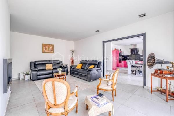 Élevée et baignée de lumière, cette maison de 124 m² de surface habitable, offrant 175 m² de surface utile au total avec buanderie et garage, récente offre une vraie vie de famille chic et pratique, à deux pas des commodités de Champigny.

Les atouts qui font la différence

Entrée majestueuse: on gravit quelques marches et l’on découvre un grand séjour traversant, chaleureux, ouvert sur la terrasse surélevée – parfait pour recevoir.
Cuisine esprit « family room »: moderne, entièrement équipée, conviviale autour de la table centrale.
Salon cocooning avec cheminée: belles soirées assurées hiver comme été.

Rez‑de‑jardin polyvalent

- Chambre indépendante parfaite pour télétravail, ado ou invités.
- Couloir avec rangements intégrés très pratiques.
-  Salle d’eau avec douche et WC.
- Buanderie attenante.
- Grand garage motorisé + portail électrique, borne de recharge pour véhicule électrique.

Étage nuit

- Deux chambres confortables avec rangements, traversantes, équipées de Velux et volets roulants électriques pour une lumière maîtrisée et un confort optimal.
- Spacieuse salle de bains: baignoire, douche, double vasque.
- WC séparés.

Confort et équipements

- Jardin paysager, impeccablement entretenu, sans vis‑à‑vis: véritable prolongement du séjour pour des réceptions élégantes.
 - Espace latéral prêt à vivre (eau + électricité): parfait pour imaginer une cuisine d’été raffinée, un jacuzzi ou un lounge extérieur.
- Fermetures premium: volets roulants électriques sur baies et Velux, double vitrage performant, éclairages encastrés.
- Stationnement d’exception: double garage fermé avec porte motorisée, portail d’entrée électrique pour un accès fluide et sécurisé.
- Mobilité de demain: borne de recharge pour véhicule électrique intégrée.
- Praticité quotidienne: buanderie dédiée, rangements généreux, matériaux choisis pour leur durabilité et leur facilité d’entretien.
- Chauffage performant: chaudière gaz à condensation Frisquet avec plancher chauffant, complétée par un insert bois pour l’appoint; production d’eau chaude couplée à la chaudière.

 Dans un secteur résidentiel recherché, cette maison clé en main marie style, confort et prestations haut de gamme, dedans comme dehors. 
Dossier complet (plans, surfaces, diagnostics) et visites privées sur rendez‑vous. Un bien rare, à découvrir sans tarder.