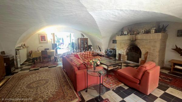 Dominant un environnement naturel préservé, cette propriété remarquable, autrefois intégrée au prestigieux château de Montréal, constitue un témoignage rare de l'architecture médiévale ardéchoise. Édifiée autour d'un authentique donjon du XIIᵉ siècle, elle offre aujourd'hui un subtil équilibre entre patrimoine historique, élégance et qualité de vie.

Développant près de 350 m² habitables, la propriété se compose d'une vaste habitation principale complétée par deux appartements indépendants, tous deux référencés Gîtes de France, permettant d'envisager une activité d'accueil de qualité ou de recevoir famille et invités dans des conditions privilégiées.

La partie la plus ancienne de la demeure a conservé des éléments architecturaux d'une rare authenticité. On y découvre un magnifique plafond voûté, un sol d'origine, des cloisons en pierre ainsi qu'un remarquable escalier médiéval, admirablement préservés. Ces éléments confèrent à la propriété une identité exceptionnelle et plongent immédiatement le visiteur dans plusieurs siècles d'histoire.

Le domaine s'étend sur plus de 8 000 m², aménagés en restanques, ces terrasses de pierre typiques des paysages ardéchois qui structurent harmonieusement le relief et offrent une succession d'espaces intimistes baignés de lumière.

Le parc, véritable jardin botanique à ciel ouvert, rassemble plus de trente essences d'arbres différentes, fruitières et ornementales, offrant un spectacle renouvelé au fil des saisons. Vergers, arbres d'ombrage, bambouseraie et végétation méditerranéenne composent un environnement d'une richesse remarquable, traversé par une source naturelle qui apporte fraîcheur et sérénité à l'ensemble de la propriété.

Parfaitement intégrée à cet écrin de verdure, une piscine de 8 x 4 mètres invite à la détente dans un cadre d'une rare tranquillité.

Les propriétaires ont constamment veillé à préserver et valoriser cette demeure au fil des années. La toiture a été entièrement refaite, le chauffage est assuré par une pompe à chaleur air/eau performante et les ouvertures sont équipées de moustiquaires, garantissant un confort contemporain sans jamais altérer le caractère des lieux.

Située à quelques minutes seulement du cœur historique de Largentière, cette propriété bénéficie d'un emplacement privilégié, offrant un parfait équilibre entre intimité, nature et proximité des commerces et services.

Rare sur le marché, cette demeure séduira les amateurs de patrimoine, d'architecture et de nature en quête d'un lieu de vie singulier ou d'une résidence de prestige à fort potentiel touristique. Plus qu'une propriété, c'est un véritable fragment d'histoire où l'authenticité médiévale dialogue harmonieusement avec le confort d'aujourd'hui, au cœur d'un domaine paysager d'une beauté exceptionnelle.