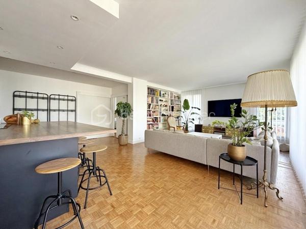 Au cœur de la très recherchée résidence La Roseraie, véritable écrin de verdure apprécié des familles, découvrez ce magnifique appartement de 131 m² entièrement rénové, offrant 4 chambres et près de 50 m² de terrasse en triple exposition. Ici, tout se fait à pied : l’école, la boulangerie, le bus et le Tram 13 ne sont qu’à quelques minutes, ce qui vous permettra peut-être même de gagner quelques précieuses minutes de sommeil le matin !

Dès l’entrée, la lumière s’invite partout grâce aux nombreuses baies vitrées d’angle qui baignent la pièce de vie d’une atmosphère chaleureuse et élégante, quelle que soit la saison. La cuisine ouverte, parfaitement équipée, s’organise autour d’un superbe îlot central avec plaques de cuisson et hotte intégrée, un espace idéal pour cuisiner, partager et recevoir sans jamais être isolé de ses invités. Un WC indépendant complète cet espace de vie convivial.

L’appartement propose également une véritable suite parentale indépendante avec une chambre d’environ 15 m², des rangements intégrés et une belle salle d’eau contemporaine avec douche à l’italienne et espace buanderie. De l’autre côté, un espace nuit dédié aux enfants ou aux invités dessert trois chambres supplémentaires ainsi qu’une seconde salle d’eau avec WC.

Le véritable luxe de cet appartement ? Sa terrasse qui entoure le logement sur trois côtés. Toutes les pièces principales y ont un accès direct, permettant de profiter du soleil à toute heure de la journée. Café du matin à l’est, déjeuner au sud, apéritif au coucher du soleil à l’ouest : il ne vous restera plus qu’à choisir votre exposition préférée.

La rénovation, particulièrement soignée, apporte un niveau de confort et de prestations rarement rencontré sur le secteur. Menuiseries aluminium double vitrage, volets roulants électriques, deux places de stationnement en sous-sol et deux caves viennent compléter ce bien. Et pour les beaux jours, la piscine de la résidence promet de beaux moments en famille sans avoir à charger la voiture de serviettes, parasols et bouées.

Un appartement rare, lumineux et parfaitement situé, qui réunit tous les ingrédients d’une vie de famille confortable dans un cadre privilégié. Une visite suffira pour comprendre pourquoi certains habitants de La Roseraie ne veulent plus la quitter.