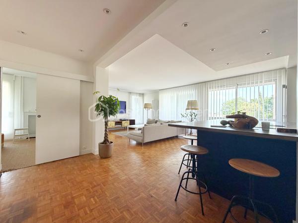 Au cœur de la très recherchée résidence La Roseraie, véritable écrin de verdure apprécié des familles, découvrez ce magnifique appartement de 131 m² entièrement rénové, offrant 4 chambres et près de 50 m² de terrasse en triple exposition. Ici, tout se fait à pied : l’école, la boulangerie, le bus et le Tram 13 ne sont qu’à quelques minutes, ce qui vous permettra peut-être même de gagner quelques précieuses minutes de sommeil le matin !

Dès l’entrée, la lumière s’invite partout grâce aux nombreuses baies vitrées d’angle qui baignent la pièce de vie d’une atmosphère chaleureuse et élégante, quelle que soit la saison. La cuisine ouverte, parfaitement équipée, s’organise autour d’un superbe îlot central avec plaques de cuisson et hotte intégrée, un espace idéal pour cuisiner, partager et recevoir sans jamais être isolé de ses invités. Un WC indépendant complète cet espace de vie convivial.

L’appartement propose également une véritable suite parentale indépendante avec une chambre d’environ 15 m², des rangements intégrés et une belle salle d’eau contemporaine avec douche à l’italienne et espace buanderie. De l’autre côté, un espace nuit dédié aux enfants ou aux invités dessert trois chambres supplémentaires ainsi qu’une seconde salle d’eau avec WC.

Le véritable luxe de cet appartement ? Sa terrasse qui entoure le logement sur trois côtés. Toutes les pièces principales y ont un accès direct, permettant de profiter du soleil à toute heure de la journée. Café du matin à l’est, déjeuner au sud, apéritif au coucher du soleil à l’ouest : il ne vous restera plus qu’à choisir votre exposition préférée.

La rénovation, particulièrement soignée, apporte un niveau de confort et de prestations rarement rencontré sur le secteur. Menuiseries aluminium double vitrage, volets roulants électriques, deux places de stationnement en sous-sol et deux caves viennent compléter ce bien. Et pour les beaux jours, la piscine de la résidence promet de beaux moments en famille sans avoir à charger la voiture de serviettes, parasols et bouées.

Un appartement rare, lumineux et parfaitement situé, qui réunit tous les ingrédients d’une vie de famille confortable dans un cadre privilégié. Une visite suffira pour comprendre pourquoi certains habitants de La Roseraie ne veulent plus la quitter.