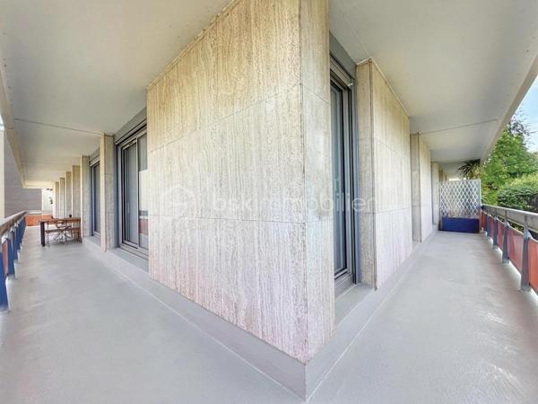 Au cœur de la très recherchée résidence La Roseraie, véritable écrin de verdure apprécié des familles, découvrez ce magnifique appartement de 131 m² entièrement rénové, offrant 4 chambres et près de 50 m² de terrasse en triple exposition. Ici, tout se fait à pied : l’école, la boulangerie, le bus et le Tram 13 ne sont qu’à quelques minutes, ce qui vous permettra peut-être même de gagner quelques précieuses minutes de sommeil le matin !

Dès l’entrée, la lumière s’invite partout grâce aux nombreuses baies vitrées d’angle qui baignent la pièce de vie d’une atmosphère chaleureuse et élégante, quelle que soit la saison. La cuisine ouverte, parfaitement équipée, s’organise autour d’un superbe îlot central avec plaques de cuisson et hotte intégrée, un espace idéal pour cuisiner, partager et recevoir sans jamais être isolé de ses invités. Un WC indépendant complète cet espace de vie convivial.

L’appartement propose également une véritable suite parentale indépendante avec une chambre d’environ 15 m², des rangements intégrés et une belle salle d’eau contemporaine avec douche à l’italienne et espace buanderie. De l’autre côté, un espace nuit dédié aux enfants ou aux invités dessert trois chambres supplémentaires ainsi qu’une seconde salle d’eau avec WC.

Le véritable luxe de cet appartement ? Sa terrasse qui entoure le logement sur trois côtés. Toutes les pièces principales y ont un accès direct, permettant de profiter du soleil à toute heure de la journée. Café du matin à l’est, déjeuner au sud, apéritif au coucher du soleil à l’ouest : il ne vous restera plus qu’à choisir votre exposition préférée.

La rénovation, particulièrement soignée, apporte un niveau de confort et de prestations rarement rencontré sur le secteur. Menuiseries aluminium double vitrage, volets roulants électriques, deux places de stationnement en sous-sol et deux caves viennent compléter ce bien. Et pour les beaux jours, la piscine de la résidence promet de beaux moments en famille sans avoir à charger la voiture de serviettes, parasols et bouées.

Un appartement rare, lumineux et parfaitement situé, qui réunit tous les ingrédients d’une vie de famille confortable dans un cadre privilégié. Une visite suffira pour comprendre pourquoi certains habitants de La Roseraie ne veulent plus la quitter.