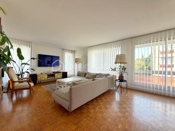 Au cœur de la très recherchée résidence La Roseraie, véritable écrin de verdure apprécié des familles, découvrez ce magnifique appartement de 131 m² entièrement rénové, offrant 4 chambres et près de 50 m² de terrasse en triple exposition. Ici, tout se fait à pied : l’école, la boulangerie, le bus et le Tram 13 ne sont qu’à quelques minutes, ce qui vous permettra peut-être même de gagner quelques précieuses minutes de sommeil le matin !

Dès l’entrée, la lumière s’invite partout grâce aux nombreuses baies vitrées d’angle qui baignent la pièce de vie d’une atmosphère chaleureuse et élégante, quelle que soit la saison. La cuisine ouverte, parfaitement équipée, s’organise autour d’un superbe îlot central avec plaques de cuisson et hotte intégrée, un espace idéal pour cuisiner, partager et recevoir sans jamais être isolé de ses invités. Un WC indépendant complète cet espace de vie convivial.

L’appartement propose également une véritable suite parentale indépendante avec une chambre d’environ 15 m², des rangements intégrés et une belle salle d’eau contemporaine avec douche à l’italienne et espace buanderie. De l’autre côté, un espace nuit dédié aux enfants ou aux invités dessert trois chambres supplémentaires ainsi qu’une seconde salle d’eau avec WC.

Le véritable luxe de cet appartement ? Sa terrasse qui entoure le logement sur trois côtés. Toutes les pièces principales y ont un accès direct, permettant de profiter du soleil à toute heure de la journée. Café du matin à l’est, déjeuner au sud, apéritif au coucher du soleil à l’ouest : il ne vous restera plus qu’à choisir votre exposition préférée.

La rénovation, particulièrement soignée, apporte un niveau de confort et de prestations rarement rencontré sur le secteur. Menuiseries aluminium double vitrage, volets roulants électriques, deux places de stationnement en sous-sol et deux caves viennent compléter ce bien. Et pour les beaux jours, la piscine de la résidence promet de beaux moments en famille sans avoir à charger la voiture de serviettes, parasols et bouées.

Un appartement rare, lumineux et parfaitement situé, qui réunit tous les ingrédients d’une vie de famille confortable dans un cadre privilégié. Une visite suffira pour comprendre pourquoi certains habitants de La Roseraie ne veulent plus la quitter.