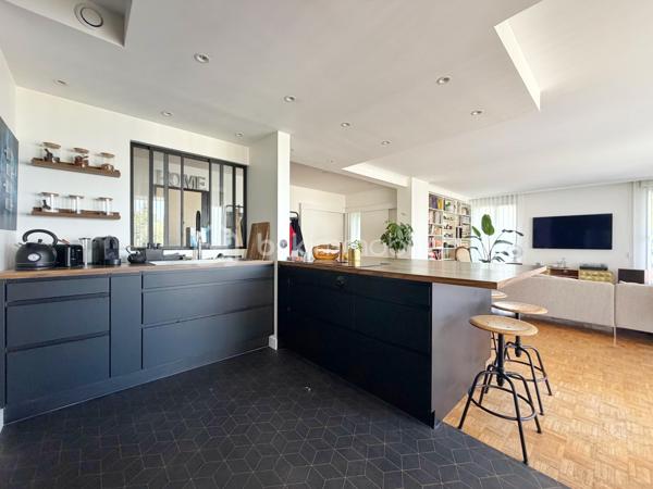 Au cœur de la très recherchée résidence La Roseraie, véritable écrin de verdure apprécié des familles, découvrez ce magnifique appartement de 131 m² entièrement rénové, offrant 4 chambres et près de 50 m² de terrasse en triple exposition. Ici, tout se fait à pied : l’école, la boulangerie, le bus et le Tram 13 ne sont qu’à quelques minutes, ce qui vous permettra peut-être même de gagner quelques précieuses minutes de sommeil le matin !

Dès l’entrée, la lumière s’invite partout grâce aux nombreuses baies vitrées d’angle qui baignent la pièce de vie d’une atmosphère chaleureuse et élégante, quelle que soit la saison. La cuisine ouverte, parfaitement équipée, s’organise autour d’un superbe îlot central avec plaques de cuisson et hotte intégrée, un espace idéal pour cuisiner, partager et recevoir sans jamais être isolé de ses invités. Un WC indépendant complète cet espace de vie convivial.

L’appartement propose également une véritable suite parentale indépendante avec une chambre d’environ 15 m², des rangements intégrés et une belle salle d’eau contemporaine avec douche à l’italienne et espace buanderie. De l’autre côté, un espace nuit dédié aux enfants ou aux invités dessert trois chambres supplémentaires ainsi qu’une seconde salle d’eau avec WC.

Le véritable luxe de cet appartement ? Sa terrasse qui entoure le logement sur trois côtés. Toutes les pièces principales y ont un accès direct, permettant de profiter du soleil à toute heure de la journée. Café du matin à l’est, déjeuner au sud, apéritif au coucher du soleil à l’ouest : il ne vous restera plus qu’à choisir votre exposition préférée.

La rénovation, particulièrement soignée, apporte un niveau de confort et de prestations rarement rencontré sur le secteur. Menuiseries aluminium double vitrage, volets roulants électriques, deux places de stationnement en sous-sol et deux caves viennent compléter ce bien. Et pour les beaux jours, la piscine de la résidence promet de beaux moments en famille sans avoir à charger la voiture de serviettes, parasols et bouées.

Un appartement rare, lumineux et parfaitement situé, qui réunit tous les ingrédients d’une vie de famille confortable dans un cadre privilégié. Une visite suffira pour comprendre pourquoi certains habitants de La Roseraie ne veulent plus la quitter.