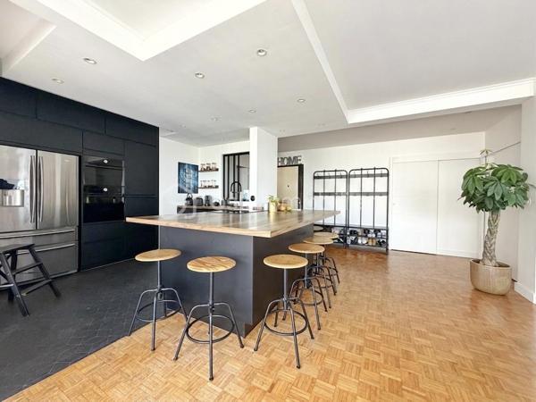 Au cœur de la très recherchée résidence La Roseraie, véritable écrin de verdure apprécié des familles, découvrez ce magnifique appartement de 131 m² entièrement rénové, offrant 4 chambres et près de 50 m² de terrasse en triple exposition. Ici, tout se fait à pied : l’école, la boulangerie, le bus et le Tram 13 ne sont qu’à quelques minutes, ce qui vous permettra peut-être même de gagner quelques précieuses minutes de sommeil le matin !

Dès l’entrée, la lumière s’invite partout grâce aux nombreuses baies vitrées d’angle qui baignent la pièce de vie d’une atmosphère chaleureuse et élégante, quelle que soit la saison. La cuisine ouverte, parfaitement équipée, s’organise autour d’un superbe îlot central avec plaques de cuisson et hotte intégrée, un espace idéal pour cuisiner, partager et recevoir sans jamais être isolé de ses invités. Un WC indépendant complète cet espace de vie convivial.

L’appartement propose également une véritable suite parentale indépendante avec une chambre d’environ 15 m², des rangements intégrés et une belle salle d’eau contemporaine avec douche à l’italienne et espace buanderie. De l’autre côté, un espace nuit dédié aux enfants ou aux invités dessert trois chambres supplémentaires ainsi qu’une seconde salle d’eau avec WC.

Le véritable luxe de cet appartement ? Sa terrasse qui entoure le logement sur trois côtés. Toutes les pièces principales y ont un accès direct, permettant de profiter du soleil à toute heure de la journée. Café du matin à l’est, déjeuner au sud, apéritif au coucher du soleil à l’ouest : il ne vous restera plus qu’à choisir votre exposition préférée.

La rénovation, particulièrement soignée, apporte un niveau de confort et de prestations rarement rencontré sur le secteur. Menuiseries aluminium double vitrage, volets roulants électriques, deux places de stationnement en sous-sol et deux caves viennent compléter ce bien. Et pour les beaux jours, la piscine de la résidence promet de beaux moments en famille sans avoir à charger la voiture de serviettes, parasols et bouées.

Un appartement rare, lumineux et parfaitement situé, qui réunit tous les ingrédients d’une vie de famille confortable dans un cadre privilégié. Une visite suffira pour comprendre pourquoi certains habitants de La Roseraie ne veulent plus la quitter.