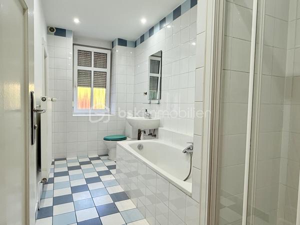 À seulement 300 mètres du centre-ville de Sarreguemines, découvrez cet appartement de plus de 83 m², situé au rez-de-chaussée d’une petite copropriété, dans une rue calme et peu passante.

L’appartement se distingue par ses beaux volumes et sa luminosité, avec notamment un agréable salon-séjour-cuisine offrant un espace de vie très confortable.

Les deux chambres, situées à l’arrière de l’appartement, bénéficient d’un environnement calme et donnent sur la cour. L’une d’elles dispose d’un accès direct et privatif à la salle de bains, équipée à la fois d’une douche et d’une baignoire.

L’ensemble de l’appartement vient d’être entièrement repeint. Il conserve également le charme d’un ancien parquet massif, qui mériterait d’être rénové, décapé et éventuellement revitrifié afin de retrouver tout son cachet.

La copropriété est de petite taille et bénéficie d’un syndic bénévole. L’immeuble est en bon état et les parties communes sont particulièrement bien entretenues.

Autre véritable atout : l’appartement est vendu avec deux garages, accessibles par un porche, et une grande cave. L’un des deux garages est actuellement loué, offrant ainsi un revenu locatif complémentaire à son propriétaire.