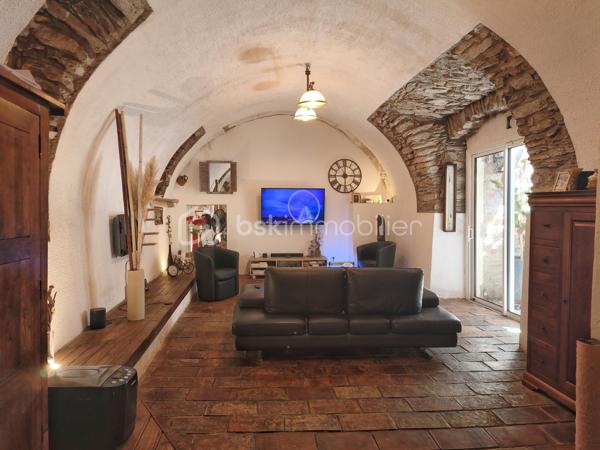 À l'entrée du village pittoresque de Faugères, au cœur d'un environnement réputé pour son vignoble AOP et sa qualité de vie, découvrez cette authentique maison en pierre de 179 m² habitables, organisée autour d'un agréable patio intérieur.
La propriété offre une configuration rare avec deux espaces de vie communicants : une habitation principale pleine de charme et une suite indépendante avec espace bien-être, idéale pour accueillir famille, amis, exercer une activité touristique ou créer un espace dédié au télétravail ou à une profession libérale.

L'habitation principale
L'entrée s'ouvre sur une spacieuse cuisine de 23 m², équipée d'une climatisation réversible et d'un poêle à granulés.
Elle mène à un superbe salon de 36 m², aménagé dans une ancienne écurie. Son plafond voûté, sa belle hauteur sous plafond et sa grande baie vitrée ouverte sur le patio lui confèrent un caractère unique.
Un WC indépendant complète le rez-de-chaussée, ainsi qu'un accès direct au garage de 35 m² équipé d'une porte motorisée.
À l'étage, une première chambre de 20,5 m² avec dressing (actuellement aménagée en bureau) précède une agréable suite parentale de 23,8 m² avec salle d'eau, double vasque, WC indépendant et climatisation.

La suite indépendante bien-être
Communicante avec la maison tout en bénéficiant d'un accès par le patio, cette seconde partie de la propriété comprend :
un salon / salle à manger de 33,65 m² avec climatisation et poêle à granulés ;
un WC indépendant ;
une vaste suite d'environ 40 m² avec salle d'eau ;
un jacuzzi privatif ;
un sauna dans une pièce attenante ;
une terrasse privée de 8 m².

Cet espace peut accueillir une activité de location saisonnière, recevoir famille et amis en toute autonomie ou encore être intégré à l'habitation principale.

Un extérieur intimiste
Véritable cœur de la maison, le patio de 31 m², à l'abri des regards, est accessible depuis les deux espaces de vie, le garage et la rue située à l'arrière de la propriété.
Il dispose d'une cuisine d'été de 5,6 m² ainsi que d'une buanderie de 5 m², parfaites pour profiter pleinement des beaux jours.

Les atouts
179 m² habitables
Deux espaces de vie communicants
Suite indépendante avec jacuzzi et sauna
Ancienne écurie rénovée avec salon voûté
Patio de 31 m²
Garage de 35 m²
Cuisine d'été
Climatisations réversibles
Deux poêles à granulés
Fibre optique
Faible taxe foncière 

Faugères offre un cadre de vie recherché entre vignobles et nature, avec école, commerces de proximité, restaurants et domaines viticoles. Béziers, Pézenas, les plages méditerranéennes et le Parc naturel régional du Haut-Languedoc sont rapidement accessibles.

Prix : 290 000 € HAI