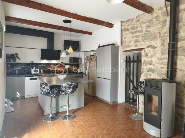 À l'entrée du village pittoresque de Faugères, au cœur d'un environnement réputé pour son vignoble AOP et sa qualité de vie, découvrez cette authentique maison en pierre de 179 m² habitables, organisée autour d'un agréable patio intérieur.
La propriété offre une configuration rare avec deux espaces de vie communicants : une habitation principale pleine de charme et une suite indépendante avec espace bien-être, idéale pour accueillir famille, amis, exercer une activité touristique ou créer un espace dédié au télétravail ou à une profession libérale.

L'habitation principale
L'entrée s'ouvre sur une spacieuse cuisine de 23 m², équipée d'une climatisation réversible et d'un poêle à granulés.
Elle mène à un superbe salon de 36 m², aménagé dans une ancienne écurie. Son plafond voûté, sa belle hauteur sous plafond et sa grande baie vitrée ouverte sur le patio lui confèrent un caractère unique.
Un WC indépendant complète le rez-de-chaussée, ainsi qu'un accès direct au garage de 35 m² équipé d'une porte motorisée.
À l'étage, une première chambre de 20,5 m² avec dressing (actuellement aménagée en bureau) précède une agréable suite parentale de 23,8 m² avec salle d'eau, double vasque, WC indépendant et climatisation.

La suite indépendante bien-être
Communicante avec la maison tout en bénéficiant d'un accès par le patio, cette seconde partie de la propriété comprend :
un salon / salle à manger de 33,65 m² avec climatisation et poêle à granulés ;
un WC indépendant ;
une vaste suite d'environ 40 m² avec salle d'eau ;
un jacuzzi privatif ;
un sauna dans une pièce attenante ;
une terrasse privée de 8 m².

Cet espace peut accueillir une activité de location saisonnière, recevoir famille et amis en toute autonomie ou encore être intégré à l'habitation principale.

Un extérieur intimiste
Véritable cœur de la maison, le patio de 31 m², à l'abri des regards, est accessible depuis les deux espaces de vie, le garage et la rue située à l'arrière de la propriété.
Il dispose d'une cuisine d'été de 5,6 m² ainsi que d'une buanderie de 5 m², parfaites pour profiter pleinement des beaux jours.

Les atouts
179 m² habitables
Deux espaces de vie communicants
Suite indépendante avec jacuzzi et sauna
Ancienne écurie rénovée avec salon voûté
Patio de 31 m²
Garage de 35 m²
Cuisine d'été
Climatisations réversibles
Deux poêles à granulés
Fibre optique
Faible taxe foncière 

Faugères offre un cadre de vie recherché entre vignobles et nature, avec école, commerces de proximité, restaurants et domaines viticoles. Béziers, Pézenas, les plages méditerranéennes et le Parc naturel régional du Haut-Languedoc sont rapidement accessibles.

Prix : 290 000 € HAI