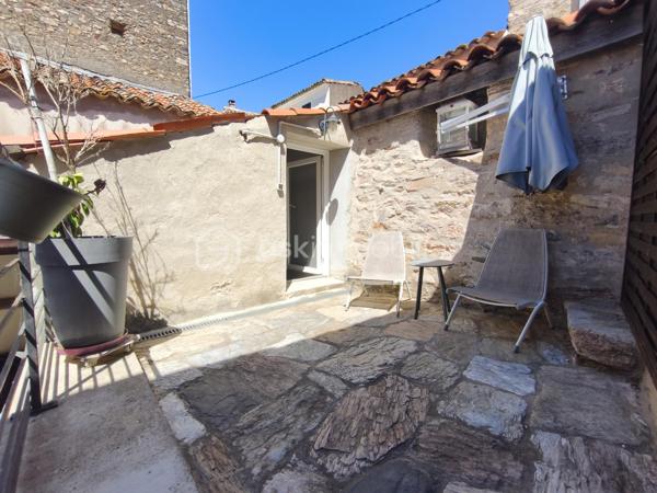 À l'entrée du village pittoresque de Faugères, au cœur d'un environnement réputé pour son vignoble AOP et sa qualité de vie, découvrez cette authentique maison en pierre de 179 m² habitables, organisée autour d'un agréable patio intérieur.
La propriété offre une configuration rare avec deux espaces de vie communicants : une habitation principale pleine de charme et une suite indépendante avec espace bien-être, idéale pour accueillir famille, amis, exercer une activité touristique ou créer un espace dédié au télétravail ou à une profession libérale.

L'habitation principale
L'entrée s'ouvre sur une spacieuse cuisine de 23 m², équipée d'une climatisation réversible et d'un poêle à granulés.
Elle mène à un superbe salon de 36 m², aménagé dans une ancienne écurie. Son plafond voûté, sa belle hauteur sous plafond et sa grande baie vitrée ouverte sur le patio lui confèrent un caractère unique.
Un WC indépendant complète le rez-de-chaussée, ainsi qu'un accès direct au garage de 35 m² équipé d'une porte motorisée.
À l'étage, une première chambre de 20,5 m² avec dressing (actuellement aménagée en bureau) précède une agréable suite parentale de 23,8 m² avec salle d'eau, double vasque, WC indépendant et climatisation.

La suite indépendante bien-être
Communicante avec la maison tout en bénéficiant d'un accès par le patio, cette seconde partie de la propriété comprend :
un salon / salle à manger de 33,65 m² avec climatisation et poêle à granulés ;
un WC indépendant ;
une vaste suite d'environ 40 m² avec salle d'eau ;
un jacuzzi privatif ;
un sauna dans une pièce attenante ;
une terrasse privée de 8 m².

Cet espace peut accueillir une activité de location saisonnière, recevoir famille et amis en toute autonomie ou encore être intégré à l'habitation principale.

Un extérieur intimiste
Véritable cœur de la maison, le patio de 31 m², à l'abri des regards, est accessible depuis les deux espaces de vie, le garage et la rue située à l'arrière de la propriété.
Il dispose d'une cuisine d'été de 5,6 m² ainsi que d'une buanderie de 5 m², parfaites pour profiter pleinement des beaux jours.

Les atouts
179 m² habitables
Deux espaces de vie communicants
Suite indépendante avec jacuzzi et sauna
Ancienne écurie rénovée avec salon voûté
Patio de 31 m²
Garage de 35 m²
Cuisine d'été
Climatisations réversibles
Deux poêles à granulés
Fibre optique
Faible taxe foncière 

Faugères offre un cadre de vie recherché entre vignobles et nature, avec école, commerces de proximité, restaurants et domaines viticoles. Béziers, Pézenas, les plages méditerranéennes et le Parc naturel régional du Haut-Languedoc sont rapidement accessibles.

Prix : 290 000 € HAI