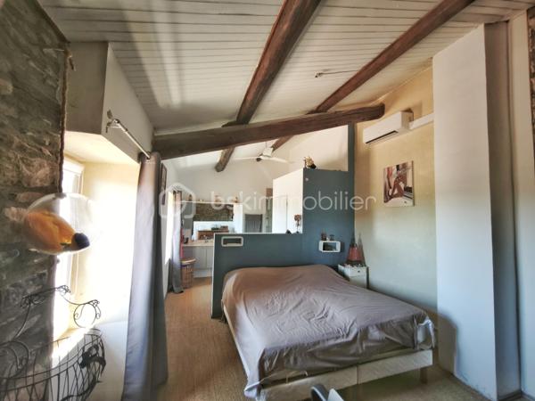 À l'entrée du village pittoresque de Faugères, au cœur d'un environnement réputé pour son vignoble AOP et sa qualité de vie, découvrez cette authentique maison en pierre de 179 m² habitables, organisée autour d'un agréable patio intérieur.
La propriété offre une configuration rare avec deux espaces de vie communicants : une habitation principale pleine de charme et une suite indépendante avec espace bien-être, idéale pour accueillir famille, amis, exercer une activité touristique ou créer un espace dédié au télétravail ou à une profession libérale.

L'habitation principale
L'entrée s'ouvre sur une spacieuse cuisine de 23 m², équipée d'une climatisation réversible et d'un poêle à granulés.
Elle mène à un superbe salon de 36 m², aménagé dans une ancienne écurie. Son plafond voûté, sa belle hauteur sous plafond et sa grande baie vitrée ouverte sur le patio lui confèrent un caractère unique.
Un WC indépendant complète le rez-de-chaussée, ainsi qu'un accès direct au garage de 35 m² équipé d'une porte motorisée.
À l'étage, une première chambre de 20,5 m² avec dressing (actuellement aménagée en bureau) précède une agréable suite parentale de 23,8 m² avec salle d'eau, double vasque, WC indépendant et climatisation.

La suite indépendante bien-être
Communicante avec la maison tout en bénéficiant d'un accès par le patio, cette seconde partie de la propriété comprend :
un salon / salle à manger de 33,65 m² avec climatisation et poêle à granulés ;
un WC indépendant ;
une vaste suite d'environ 40 m² avec salle d'eau ;
un jacuzzi privatif ;
un sauna dans une pièce attenante ;
une terrasse privée de 8 m².

Cet espace peut accueillir une activité de location saisonnière, recevoir famille et amis en toute autonomie ou encore être intégré à l'habitation principale.

Un extérieur intimiste
Véritable cœur de la maison, le patio de 31 m², à l'abri des regards, est accessible depuis les deux espaces de vie, le garage et la rue située à l'arrière de la propriété.
Il dispose d'une cuisine d'été de 5,6 m² ainsi que d'une buanderie de 5 m², parfaites pour profiter pleinement des beaux jours.

Les atouts
179 m² habitables
Deux espaces de vie communicants
Suite indépendante avec jacuzzi et sauna
Ancienne écurie rénovée avec salon voûté
Patio de 31 m²
Garage de 35 m²
Cuisine d'été
Climatisations réversibles
Deux poêles à granulés
Fibre optique
Faible taxe foncière 

Faugères offre un cadre de vie recherché entre vignobles et nature, avec école, commerces de proximité, restaurants et domaines viticoles. Béziers, Pézenas, les plages méditerranéennes et le Parc naturel régional du Haut-Languedoc sont rapidement accessibles.

Prix : 290 000 € HAI