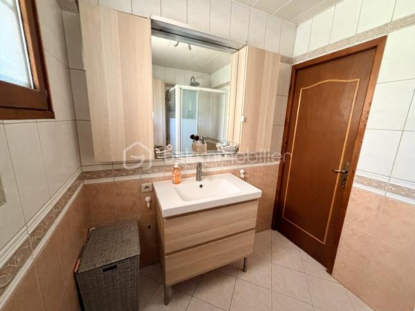 NOUVELLE OPPORTUNITÉ !

Située dans un secteur calme et recherché, cette agréable maison mitoyenne d'un côté vous séduira par ses volumes, ses nombreuses dépendances et son environnement tranquille.

Dès l'entrée, vous découvrirez une belle pièce de vie lumineuse composée d'un salon, séjour et cuisine ouverte, offrant un espace convivial idéal pour partager de beaux moments en famille.

La partie nuit comprend :
✅ 3 chambres
✅ Une salle de douche
✅ Un WC indépendant

Vous profiterez également d'une magnifique véranda en aluminium récente de 28 m², protection anti UV, véritable pièce de vie supplémentaire donnant sur le jardin.

Le sous-sol complet offre de nombreuses possibilités avec :
•	Une buanderie,
•	Un atelier,
•	Deux caves,
•	Un très grand garage pouvant accueillir jusqu'à 4 véhicules.

À l'extérieur, laissez-vous séduire par un jardin entièrement clôturé, agrémenté d'un abri de jardin (env 18 m²) et d'une cuve enterrée de récupération d'eau de 300 litres.

Les + de cette maison :
✔ Secteur recherché et paisible
✔ Véranda aluminium récente de 26 m²
✔ Garage 4 véhicules
✔ Portail motorisé
✔ Clôtures et barrières récentes (novembre 2021)
✔ Garde-corps de balcon récent
✔ Fenêtres PVC double vitrage (hors 2 fenêtres en bois double vitrage)
✔ Volets roulants électriques et volets battants
✔ Jardin clos avec vue dégagée

Informations complémentaires :
•	Maison de 90 m² habitables
•	Parcelle de 604 m²
•	Chauffage par radiateurs électriques
•	Le poêle à bois sera retiré avant la vente
•	Tubage en place pour mise en place d'un poêle / Insert
•	Taxe foncière : 820 €/an

Une maison idéale pour une famille à la recherche de tranquillité, de beaux espaces de stockage et d'un agréable extérieur.

📞 N'attendez plus pour venir la découvrir ! Contactez-moi dès aujourd'hui pour organiser votre visite.