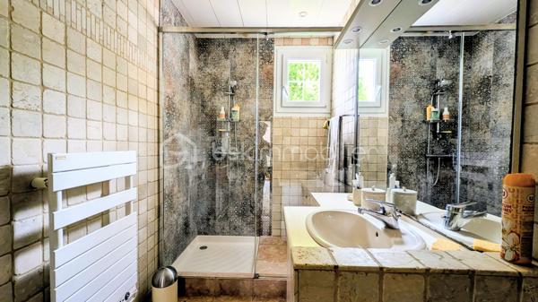 EXCLUSIVITE

Située sur la commune prisée de Douvres-la-Délivrande,  à proximité immédiate de commerces, cette belle propriété de 146 m² habitables allie le cachet de l'ancien au confort moderne. 
Elle se distingue dès l'extérieur par son architecture soignée, dotée d'une toiture en tuiles plates et d'une façade habillée de pierres de parement. 
Édifiée sur un magnifique jardin arboré de 900 m², elle offre de superbes volumes et un agencement idéal.

 Les Caractéristiques Clés

 * Surface habitable : 146 m²
 * Surface du terrain : 900 m²
 * Nombre de chambres : 5 (dont une au rez-de-chaussée)
 * Sous-sol total : 85 m²

 L'Agencement Intérieur
Au rez-de-chaussée (entièrement revêtu de tomettes authentiques et des poutres apparentes dans l'entrée) :
 * Une vaste pièce de vie de 38 m², chaleureuse et lumineuse grâce à sa triple exposition, agrémentée d'un poêle à pellets.
 * Une cuisine aménagée et parfaitement équipée.
 * Une chambre et une salle d'eau , permettant une vie de plain-pied confortable.

*À l'étage (desservi par un escalier et un palier conservant le charme des tomettes) :
 * Quatre belles chambres, dont une particulièrement spacieuse de plus de 20 m² habitables.
 * Une salle de bains indépendante équipée d'une baignoire.
 * Un WC séparé.

 Le Sous-Sol Complet (85 m²)
 * Un vaste garage d'environ 35 m².
 * Une très grande pièce de 40 m², offrant de multiples possibilités d'aménagement (atelier, salle de jeux, espace de stockage).

 Énergie et Fiscalité
 * Système de chauffage : Électrique couplé à un poêle à pellets pour un confort optimal.
 * Consommation énergétique réelle : Environ 2000 €/an d'électricité et 480 €/an de pellets (une consommation avérée largement inférieure aux estimations du DPE).
 * Taxe foncière : 2200 €

Vous n'avez plus qu'a mettre vos meubles et savourer le bonheur de vivre ici!