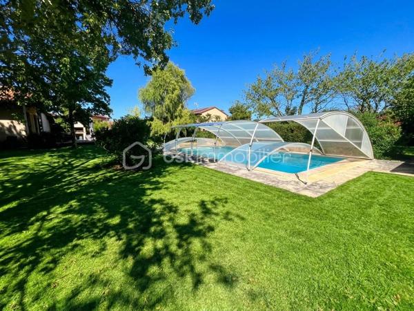 Laissez-vous charmer par cette pépite architecturale des années 80, édifiée au cœur d'un somptueux parc arboré et paysagé de près de 3 100 m², parsemé d'arbres fruitiers. Une véritable oasis de paix et de verdure, sans aucun vis-à-vis.
Dès le franchissement de la porte, cette propriété d'environ 180 m² habitables impose son style unique et ses volumes généreux. Le cœur de la maison s'articule autour d'une spectaculaire pièce de vie cathédrale sublimée par ses poutres apparentes et sa cheminée d'époque, insufflant une atmosphère à la fois chaleureuse et résolument authentique.


Côté intérieur : des prestations familiales et fonctionnelles

De plain-pied :
     Un vaste séjour cathédrale baigné de lumière avec cheminée.
     Une cuisine / des espaces de vie fluides complétés par 3 chambres confortables.
     Une salle de bains, un bureau (idéal télétravail), une buanderie et un garde-manger.
     Une agréable véranda, parfaite pour prolonger les soirées d'automne ou profiter des journées ensoleillées.

 À l’étage :
     Une élégante mezzanine en surplomb, offrant un espace lecture ou détente baigné de cachet.
     Une quatrième chambre supplémentaire et une salle d’eau privative.

Côté extérieur : un art de vivre privilégié

Le spectacle se poursuit dehors avec ce immense jardin arboré, véritable terrain de jeux ou havre de sérénité. Pour parfaire les beaux jours, une très grande piscine invite à la détente et aux moments de partage en famille ou entre amis.

Un garage double indépendant vient compléter les prestations de ce bien d'exception.
Les prestations techniques & Confort :
Surface habitable : 180 m2 Terrain : 3 100 m2 Divisible
 Chauffage : Électrique + climatisation réversible
Eau chaude : Ballon électrique
 Menuiseries : Double vitrage
 Stationnement : Garage double (2 places)

Une propriété rare sur le marché, alliance parfaite entre le charme de l'ancien revisité, l'architecture d'auteur et la quiétude de la nature.