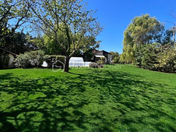 Laissez-vous charmer par cette pépite architecturale des années 80, édifiée au cœur d'un somptueux parc arboré et paysagé de près de 3 100 m², parsemé d'arbres fruitiers. Une véritable oasis de paix et de verdure, sans aucun vis-à-vis.
Dès le franchissement de la porte, cette propriété d'environ 180 m² habitables impose son style unique et ses volumes généreux. Le cœur de la maison s'articule autour d'une spectaculaire pièce de vie cathédrale sublimée par ses poutres apparentes et sa cheminée d'époque, insufflant une atmosphère à la fois chaleureuse et résolument authentique.


Côté intérieur : des prestations familiales et fonctionnelles

De plain-pied :
     Un vaste séjour cathédrale baigné de lumière avec cheminée.
     Une cuisine / des espaces de vie fluides complétés par 3 chambres confortables.
     Une salle de bains, un bureau (idéal télétravail), une buanderie et un garde-manger.
     Une agréable véranda, parfaite pour prolonger les soirées d'automne ou profiter des journées ensoleillées.

 À l’étage :
     Une élégante mezzanine en surplomb, offrant un espace lecture ou détente baigné de cachet.
     Une quatrième chambre supplémentaire et une salle d’eau privative.

Côté extérieur : un art de vivre privilégié

Le spectacle se poursuit dehors avec ce immense jardin arboré, véritable terrain de jeux ou havre de sérénité. Pour parfaire les beaux jours, une très grande piscine invite à la détente et aux moments de partage en famille ou entre amis.

Un garage double indépendant vient compléter les prestations de ce bien d'exception.
Les prestations techniques & Confort :
Surface habitable : 180 m2 Terrain : 3 100 m2 Divisible
 Chauffage : Électrique + climatisation réversible
Eau chaude : Ballon électrique
 Menuiseries : Double vitrage
 Stationnement : Garage double (2 places)

Une propriété rare sur le marché, alliance parfaite entre le charme de l'ancien revisité, l'architecture d'auteur et la quiétude de la nature.