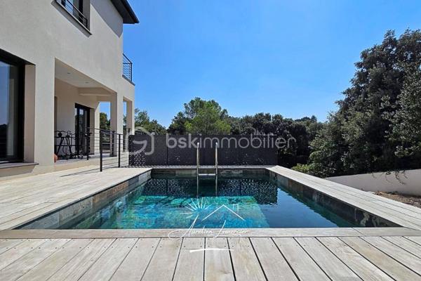 À Poulx, situé a quelques minutes de Nîmes, cette maison contemporaine construite en 2024 se dévoile dans un environnement paisible, légèrement en hauteur, avec une vue dégagée qui donne immédiatement le ton. Dès l’extérieur, les lignes sont modernes, sobres et élégantes. La maison est non mitoyenne, parfaitement intégrée à son terrain d’environ 450 m², avec des aménagements pensés pour la tranquillité et la facilité d’entretien.

On accède à la maison par un cheminement soigné, où l’on perçoit tout de suite la qualité de la construction. Le stationnement est simple et confortable, avec plusieurs places de parking et un garage spacieux de 28 m², directement accessible depuis la maison.

À l’intérieur, la lumière est omniprésente. La pièce de vie offre de beaux volumes et une circulation fluide entre les espaces. Le séjour s’ouvre largement sur l’extérieur grâce à de grandes baies vitrées, laissant entrer la lumière naturelle tout au long de la journée et offrant une vue apaisante sur la végétation environnante. La cuisine, moderne et entièrement équipée, s’intègre parfaitement à l’ensemble, créant un lieu convivial où l’on imagine facilement les repas en famille ou entre amis.

Depuis la pièce de vie, la maison se prolonge naturellement vers l’extérieur. La coursive mène à une terrasse accueillante, au jardin et à la piscine, véritable cœur de la maison dès les beaux jours. Un espace pensé pour profiter pleinement du climat, se détendre, recevoir et vivre dehors autant que dedans.

À l’étage, l’ambiance devient plus intime. Trois chambres confortables composent l’espace nuit, accompagnées d’une salle de bain. La terrasse accessible depuis l’étage offre une vue dégagée sur les environs, un endroit idéal pour savourer un café le matin ou un moment de calme en fin de journée, face à un paysage ouvert et verdoyant.

Le niveau inférieur apporte une vraie modularité à la maison. Une chambre avec sa salle d’eau permet d’accueillir famille, amis ou de créer un espace indépendant, tout en conservant un accès direct au garage. Un agencement particulièrement pratique au quotidien.

Côté prestations, la maison répond aux standards actuels de confort et de performance. Climatisation réversible gainable, ballon thermodynamique, double vitrage, volets roulants électriques… Tout a été pensé pour offrir une maison économe, agréable à vivre et sans aucun travaux à prévoir.

Cette propriété s’adresse à ceux qui recherchent une maison neuve, contemporaine et lumineuse, avec des volumes généreux, des extérieurs soignés et une vraie qualité de vie, dans un secteur calme tout en restant proche de Nîmes.

Un bien où chaque espace a été pensé pour être vécu… et apprécié.

Pour plus d’informations ou organiser une visite, je suis disponible 24h/24 et 7j/7.
Contactez-moi directement au O6 20 75 00 O7.
