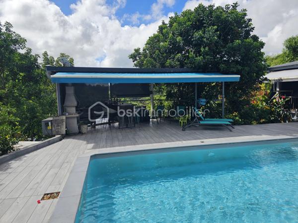Jérôme MIGLIORE pour BSK Immobilier vous propose à la vente :

ENSEMBLE IMMOBILIER  – UN LIEU DE VIE, UN POTENTIEL PROFESSIONNEL ET UNE ACTIVITÉ TOURISTIQUE DÉJÀ RENTABLE

Entre Sainte-Anne et Le Moule – Magnifique propriété arborée de 3 000 m²

Il est des biens qui offrent bien plus qu’un simple lieu de résidence.
Cet ensemble immobilier rare, niché dans un environnement verdoyant et préservé entre Sainte-Anne et Le Moule, conjugue harmonieusement qualité de vie, indépendance, potentiel de développement et rentabilité locative.
Implantée sur un magnifique terrain arboré de 3 000 m², cette propriété  de 300 m2 de bâti environ constitue une véritable opportunité pour une famille en quête d’espace, un investisseur à la recherche de revenus complémentaires ou un professionnel souhaitant développer son activité sur place.
	
L’ensemble comprend une résidence principale, deux hébergements touristiques indépendants, un bureau, ainsi que de généreux espaces annexes dédiés au stockage, au bricolage ou à une activité professionnelle.

UNE RÉSIDENCE PRINCIPALE AUX ACCENTS TROPICAUX
Développant une surface annoncée de 215 m² habitables pour l’ensemble immobilier, dont une maison principale offrant aujourd’hui 137 m² de surface de vie, cette habitation séduit par ses volumes, son agencement et son ouverture sur l’extérieur.
Elle propose trois chambres climatisées, une mezzanine de 15 m² pouvant accueillir des couchages supplémentaires, deux salles d’eau, deux WC, ainsi qu’un séjour de 36 m² propice aux moments de convivialité.
La cuisine indépendante et aménagée complète cet espace de vie fonctionnel et agréable.
Dans le prolongement de la maison, une vaste terrasse de 57 m² invite à profiter pleinement du climat guadeloupéen, avec une perspective dégagée sur les espaces extérieurs.

UN ESPACE EXTÉRIEUR DÉDIÉ À LA DÉTENTE
Véritable invitation au farniente, l’espace piscine constitue l’un des atouts majeurs de la propriété.
Piscine au sel chauffée de 8 x 4 mètres, grand deck, bar extérieur et barbecue composent un cadre idéal pour recevoir famille et amis ou séduire une clientèle touristique en quête d’un séjour sous le soleil des Antilles.
Le terrain, richement arboré et agrémenté de nombreux citronniers, bénéficie d’une absence de vis-à-vis, garantissant intimité et tranquillité.
Les citronniers procurent actuellement un revenu complémentaire, ajoutant une dimension productive à cet environnement privilégié.

UN POTENTIEL LOCATIF DÉJÀ EN PLACE
L’un des points forts de cet ensemble réside dans la présence de deux hébergements indépendants : un studio de 36 m2 et un appartement de type T2 de 42 m2 avec son  jacuzzi et sa terrasse.
Déjà exploités dans le cadre d’une activité de location touristique, ils permettent d'envisager la poursuite d’une activité génératrice de revenus, tout en préservant l’intimité des occupants de la résidence principale.
Cette configuration se prête particulièrement à un projet de vie associant résidence familiale et activité professionnelle, avec la possibilité de développer ou d’optimiser l’exploitation selon les objectifs du futur acquéreur.
La possibilité d’une transmission de l’activité existante pourra également être étudiée.

DES DÉPENDANCES AUX MULTIPLES POSSIBILITÉS
La propriété dispose d’espaces annexes particulièrement intéressants pour les acquéreurs ayant besoin de surfaces complémentaires :
Un grand garage de 45 m².
Un atelier de 42 m².
Deux pièces de stockage non aménagées totalisant 29 m².
Un bureau indépendant, offrant un espace adapté au télétravail ou à une activité professionnelle.
Ces dépendances permettent d’envisager de nombreux usages : atelier artisanal, espace de travail, stockage de matériel, activité indépendante ou organisation d’une activité nécessitant des locaux sur place, sous réserve des autorisations applicables.

UN POTENTIEL DE DÉVELOPPEMENT À ÉTUDIER
Implanté en zone UG du PLU, le terrain présente un intérêt supplémentaire pour un acquéreur souhaitant envisager une évolution du patrimoine.
Selon les règles d’urbanisme applicables, les caractéristiques de la parcelle et les autorisations obtenues, des possibilités d’agrandissement ou de nouvelles constructions pourraient être étudiées.
Un potentiel qui ouvre la voie à différents projets : création d’hébergements supplémentaires, développement de l’activité touristique ou valorisation patrimoniale à plus long terme.
Le zonage et les possibilités constructives devront naturellement être confirmés auprès du service d’urbanisme compétent.

DES ÉQUIPEMENTS QUI RENFORCENT L’AUTONOMIE DU SITE
La vente comprend également plusieurs équipements professionnels et techniques :
Un groupe électrogène de 15 kVA.
Un broyeur à végétaux professionnel.
Une brouette mécanisée.
Cuve de récupération des eaux pluviales.
La toiture et la piscine datent de 2020.
Autre atout notable : un DPE classé B, témoignant d’une performance énergétique favorable et d’un bien peu énergivore selon son diagnostic.

UN BIEN, DE MULTIPLES PROJETS DE VIE
Cette propriété s’adresse à des acquéreurs qui souhaitent donner une nouvelle dimension à leur investissement immobilier.
Pour une famille, elle offre un cadre de vie privilégié, de beaux espaces extérieurs, une piscine et la possibilité de bénéficier de revenus locatifs.
Pour un investisseur, elle présente une activité touristique déjà en place, des hébergements indépendants et des perspectives de développement à étudier.
Pour un entrepreneur ou un indépendant, elle permet d’envisager une installation associant habitation, bureau, atelier et espaces de stockage sur un même site.
Pour un porteur de projet touristique, elle constitue une base existante à partir de laquelle envisager une évolution de l’offre, sous réserve de faisabilité réglementaire.
Pour un acquéreur patrimonial, enfin, la superficie du terrain, les dépendances et le potentiel constructible éventuel représentent autant de pistes de valorisation.

UNE OPPORTUNITÉ RARE POUR CONJUGUER ART DE VIVRE ET PROJET PROFESSIONNEL.