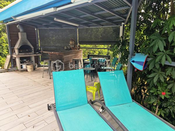 Jérôme MIGLIORE pour BSK Immobilier vous propose à la vente :

ENSEMBLE IMMOBILIER  – UN LIEU DE VIE, UN POTENTIEL PROFESSIONNEL ET UNE ACTIVITÉ TOURISTIQUE DÉJÀ RENTABLE

Entre Sainte-Anne et Le Moule – Magnifique propriété arborée de 3 000 m²

Il est des biens qui offrent bien plus qu’un simple lieu de résidence.
Cet ensemble immobilier rare, niché dans un environnement verdoyant et préservé entre Sainte-Anne et Le Moule, conjugue harmonieusement qualité de vie, indépendance, potentiel de développement et rentabilité locative.
Implantée sur un magnifique terrain arboré de 3 000 m², cette propriété  de 300 m2 de bâti environ constitue une véritable opportunité pour une famille en quête d’espace, un investisseur à la recherche de revenus complémentaires ou un professionnel souhaitant développer son activité sur place.
	
L’ensemble comprend une résidence principale, deux hébergements touristiques indépendants, un bureau, ainsi que de généreux espaces annexes dédiés au stockage, au bricolage ou à une activité professionnelle.

UNE RÉSIDENCE PRINCIPALE AUX ACCENTS TROPICAUX
Développant une surface annoncée de 215 m² habitables pour l’ensemble immobilier, dont une maison principale offrant aujourd’hui 137 m² de surface de vie, cette habitation séduit par ses volumes, son agencement et son ouverture sur l’extérieur.
Elle propose trois chambres climatisées, une mezzanine de 15 m² pouvant accueillir des couchages supplémentaires, deux salles d’eau, deux WC, ainsi qu’un séjour de 36 m² propice aux moments de convivialité.
La cuisine indépendante et aménagée complète cet espace de vie fonctionnel et agréable.
Dans le prolongement de la maison, une vaste terrasse de 57 m² invite à profiter pleinement du climat guadeloupéen, avec une perspective dégagée sur les espaces extérieurs.

UN ESPACE EXTÉRIEUR DÉDIÉ À LA DÉTENTE
Véritable invitation au farniente, l’espace piscine constitue l’un des atouts majeurs de la propriété.
Piscine au sel chauffée de 8 x 4 mètres, grand deck, bar extérieur et barbecue composent un cadre idéal pour recevoir famille et amis ou séduire une clientèle touristique en quête d’un séjour sous le soleil des Antilles.
Le terrain, richement arboré et agrémenté de nombreux citronniers, bénéficie d’une absence de vis-à-vis, garantissant intimité et tranquillité.
Les citronniers procurent actuellement un revenu complémentaire, ajoutant une dimension productive à cet environnement privilégié.

UN POTENTIEL LOCATIF DÉJÀ EN PLACE
L’un des points forts de cet ensemble réside dans la présence de deux hébergements indépendants : un studio de 36 m2 et un appartement de type T2 de 42 m2 avec son  jacuzzi et sa terrasse.
Déjà exploités dans le cadre d’une activité de location touristique, ils permettent d'envisager la poursuite d’une activité génératrice de revenus, tout en préservant l’intimité des occupants de la résidence principale.
Cette configuration se prête particulièrement à un projet de vie associant résidence familiale et activité professionnelle, avec la possibilité de développer ou d’optimiser l’exploitation selon les objectifs du futur acquéreur.
La possibilité d’une transmission de l’activité existante pourra également être étudiée.

DES DÉPENDANCES AUX MULTIPLES POSSIBILITÉS
La propriété dispose d’espaces annexes particulièrement intéressants pour les acquéreurs ayant besoin de surfaces complémentaires :
Un grand garage de 45 m².
Un atelier de 42 m².
Deux pièces de stockage non aménagées totalisant 29 m².
Un bureau indépendant, offrant un espace adapté au télétravail ou à une activité professionnelle.
Ces dépendances permettent d’envisager de nombreux usages : atelier artisanal, espace de travail, stockage de matériel, activité indépendante ou organisation d’une activité nécessitant des locaux sur place, sous réserve des autorisations applicables.

UN POTENTIEL DE DÉVELOPPEMENT À ÉTUDIER
Implanté en zone UG du PLU, le terrain présente un intérêt supplémentaire pour un acquéreur souhaitant envisager une évolution du patrimoine.
Selon les règles d’urbanisme applicables, les caractéristiques de la parcelle et les autorisations obtenues, des possibilités d’agrandissement ou de nouvelles constructions pourraient être étudiées.
Un potentiel qui ouvre la voie à différents projets : création d’hébergements supplémentaires, développement de l’activité touristique ou valorisation patrimoniale à plus long terme.
Le zonage et les possibilités constructives devront naturellement être confirmés auprès du service d’urbanisme compétent.

DES ÉQUIPEMENTS QUI RENFORCENT L’AUTONOMIE DU SITE
La vente comprend également plusieurs équipements professionnels et techniques :
Un groupe électrogène de 15 kVA.
Un broyeur à végétaux professionnel.
Une brouette mécanisée.
Cuve de récupération des eaux pluviales.
La toiture et la piscine datent de 2020.
Autre atout notable : un DPE classé B, témoignant d’une performance énergétique favorable et d’un bien peu énergivore selon son diagnostic.

UN BIEN, DE MULTIPLES PROJETS DE VIE
Cette propriété s’adresse à des acquéreurs qui souhaitent donner une nouvelle dimension à leur investissement immobilier.
Pour une famille, elle offre un cadre de vie privilégié, de beaux espaces extérieurs, une piscine et la possibilité de bénéficier de revenus locatifs.
Pour un investisseur, elle présente une activité touristique déjà en place, des hébergements indépendants et des perspectives de développement à étudier.
Pour un entrepreneur ou un indépendant, elle permet d’envisager une installation associant habitation, bureau, atelier et espaces de stockage sur un même site.
Pour un porteur de projet touristique, elle constitue une base existante à partir de laquelle envisager une évolution de l’offre, sous réserve de faisabilité réglementaire.
Pour un acquéreur patrimonial, enfin, la superficie du terrain, les dépendances et le potentiel constructible éventuel représentent autant de pistes de valorisation.

UNE OPPORTUNITÉ RARE POUR CONJUGUER ART DE VIVRE ET PROJET PROFESSIONNEL.