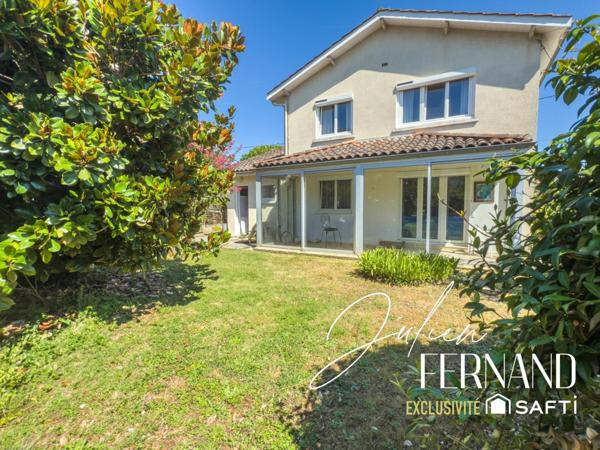Maison à étage avec garage, véranda et jardin.