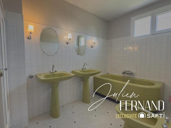 Maison à étage avec garage, véranda et jardin.