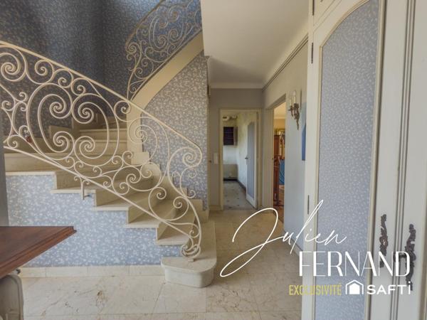 Maison à étage avec garage, véranda et jardin.