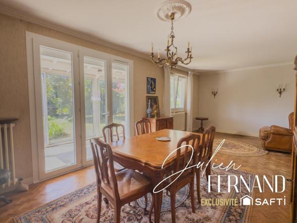 Maison à étage avec garage, véranda et jardin.