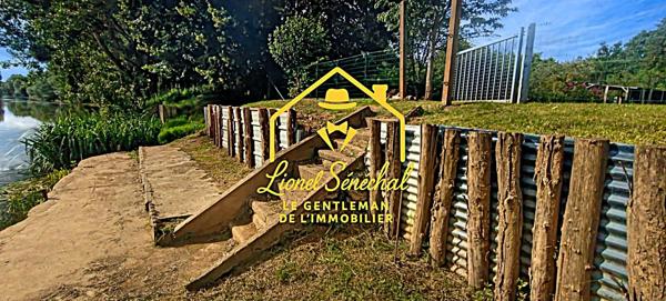 Terrain de loisirs de plus de 1 200 m2 avec un préau sur une dalle en dur, un abri de jardin et un accès direct à la rivière