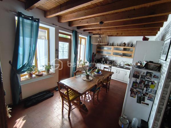 Je vous propose de découvrir cette charmante maison de 1907, pleine de caractère et très bien entretenue. Les matériaux nobles d'époque et de qualité utilisés pour la construction de ce bien vous inspireront confiance et sérénité. Véritable opportunité à saisir, cette maison idéalement située bénéficie d’un cadre paisible à proximité du centre bourg avec son école et son arrêt de bus. Les deux places de parking avec la possibilité d'installer un auvent pour abriter les véhicules sont un véritable atout pour la vie du quotidien.

Dès l'entrée, vous serez séduit par un intérieur spacieux et chaleureux. La belle hauteur sous plafond avec ses poutres apparentes et les tomettes au sol vous renverront tout le cachet de cette maison ancienne.

La visite débutera par la grande cuisine aménagée et tout équipée de 21m² alliant fonctionnalité et praticité. Un vaste salon prolonge l’espace de vie de ce rez-de-chaussée de 40m²convivial et lumineux. Une première salle d'eau se trouvant en contre-bas, accessible par quelques marches, équipée d'une douche, d'un lavabo et d'un WC saura vous ravir par son agencement et sa clarté.

Au premier étage, un agréable couloir distribuant deux chambres de 17m² et 10m² offre également une seconde salle d'eau comprenant un lavabo et un WC. La possibilité d'installer une douche permet d'envisager plus de confort à cette pièce située au cœur de cet étage.
Au fond de ce couloir, des escaliers vous mèneront à un grenier de 40m² au sol, mettant en lumière une charpente en parfait état. Ce dernier étage est entièrement aménageable, ce qui laisse entrevoir un beau potentiel d'extension de superficie habitable non négligeable.

L'extérieur d'environ 50m² très bien entretenu avec sa terrasse de 12m² et son joli jardin engazonné et arboré parachèvera cette visite. Vous pourrez vous projeter à vivre des moments de détente auprès du puits, pratique pour l'irrigation de vos plantes ou un éventuel petit potager. Un préau de 10m², pratique pour abriter le nécessaire, trouve parfaitement sa place dans cet espace privilégié.

Une opportunité rare, sans travaux immédiats à prévoir, alliant charme et potentiel. À saisir sans hésiter !
