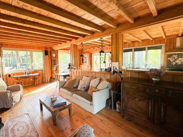 Rare à la vente, cet atelier d'artiste aménagé en maison d'habitation offre un beau potentiel à ses futurs propriétaires. 
Amoureux du bois et de la nature, ce "chalet" est fait pour vous ! Contrairement à ce que l'on pourrait penser, la structure de la maison n'est pas en bois mais en parpaing et a été enduite à la chaux. Ensuite un bardage bois a été posé. 
S'il reste aujourd'hui un atelier de peinture de 28m2 dans lequel vous pourriez aisément aussi y faire un bureau, une salle de sport, une salle de jeux ou un garage, 105m2 sont prêts à accueillir votre famille. 
Nous commencerons la visite par la pièce de vie de 45m2 qui comprend le salon-séjour et la cuisine. Une magnifique véranda chauffée "jardin d'hiver" complète cette maison, idéale pour y installer une grande table familiale ou encore un salon. 
Nous poursuivrons la visite du rez-de-chaussée avec une salle d'eau de 6m2, une chambre de 11m2. 
A l'étage, deux chambres de 12m2 au sol dont une donne accès à la "tour". 
Le mode de chauffage principal est un poêle à bois et radiateurs électriques dans la véranda et l'atelier. La maison consomme peu, le DPE est en C. 
Toutes les menuiseries sont en double vitrage. 
Coté rangement, belle surprise avec le sous-sol de 75m2, vous pourrez y stocker vélos, motos, outils et aisément un coin bricolage si vous le souhaitez. Pas de voiture possible. 
Une microstation a été installée. La toiture est en bac acier. 
Coté extérieur, vous pourrez profitez sans aucun vis à vis de la parcelle de 3300m2 partiellement close et joliment arborée et agrémentée tant par ses terrasses bois que par le bassin à poissons avec sa fontaine. 
Vous aimez le jardin, deux serres sont en place. 
La maison se situe aux portes de la Bretagne, à deux minutes de l'axe Laval-Rennes. 
Alors vous aussi vous aimez cette maison-atelier ? Appelez-moi pour plus de renseignements et peut-être fixer une visite !
