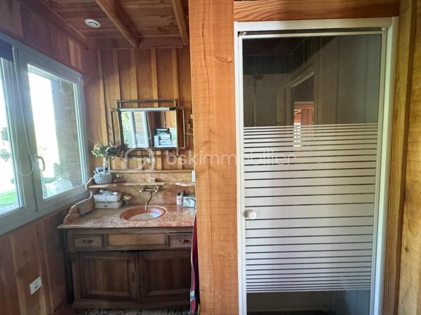 Rare à la vente, cet atelier d'artiste aménagé en maison d'habitation offre un beau potentiel à ses futurs propriétaires. 
Amoureux du bois et de la nature, ce "chalet" est fait pour vous ! Contrairement à ce que l'on pourrait penser, la structure de la maison n'est pas en bois mais en parpaing et a été enduite à la chaux. Ensuite un bardage bois a été posé. 
S'il reste aujourd'hui un atelier de peinture de 28m2 dans lequel vous pourriez aisément aussi y faire un bureau, une salle de sport, une salle de jeux ou un garage, 105m2 sont prêts à accueillir votre famille. 
Nous commencerons la visite par la pièce de vie de 45m2 qui comprend le salon-séjour et la cuisine. Une magnifique véranda chauffée "jardin d'hiver" complète cette maison, idéale pour y installer une grande table familiale ou encore un salon. 
Nous poursuivrons la visite du rez-de-chaussée avec une salle d'eau de 6m2, une chambre de 11m2. 
A l'étage, deux chambres de 12m2 au sol dont une donne accès à la "tour". 
Le mode de chauffage principal est un poêle à bois et radiateurs électriques dans la véranda et l'atelier. La maison consomme peu, le DPE est en C. 
Toutes les menuiseries sont en double vitrage. 
Coté rangement, belle surprise avec le sous-sol de 75m2, vous pourrez y stocker vélos, motos, outils et aisément un coin bricolage si vous le souhaitez. Pas de voiture possible. 
Une microstation a été installée. La toiture est en bac acier. 
Coté extérieur, vous pourrez profitez sans aucun vis à vis de la parcelle de 3300m2 partiellement close et joliment arborée et agrémentée tant par ses terrasses bois que par le bassin à poissons avec sa fontaine. 
Vous aimez le jardin, deux serres sont en place. 
La maison se situe aux portes de la Bretagne, à deux minutes de l'axe Laval-Rennes. 
Alors vous aussi vous aimez cette maison-atelier ? Appelez-moi pour plus de renseignements et peut-être fixer une visite !