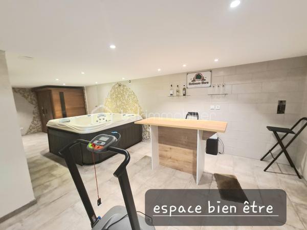Située dans un quartier calme, à proximité immédiate des écoles, des commerces et des principaux axes routiers, cette agréable maison offre de beaux volumes et de nombreuses possibilités d'aménagement. Elle conviendra aussi bien à une famille qu'à une personne souhaitant exercer une activité professionnelle à domicile.

Dès l'entrée, vous découvrirez un sas, puis une entrée accueillante. La cuisine équipée, indépendante, donne accès à un balcon-terrasse avec vue sur une magnifique piscine, utilisable toute l'année grâce à son abri télescopique Voroka avec rails encastrés.

Le rez-de-chaussée comprend également un WC indépendant, un espace de rangement, une pièce polyvalente pouvant faire office de bureau, salle de jeux ou chambre d'appoint, ainsi qu'un vaste séjour lumineux agrémenté d'une cheminée.
À l'étage, vous trouverez une chambre, un toilette indépendant, une salle de bains et une grande seconde chambre, facilement transformable en deux chambres, conformément à sa configuration d'origine.

Le sous-sol est particulièrement fonctionnel avec un garage, de nombreux espaces de rangement, une cave, une buanderie avec salle d'eau et WC, ainsi qu'un local technique équipé d'un WC et d'une douche, idéal après les baignades ou les séances bien-être.
Vous profiterez également d'un véritable espace bien-être comprenant un sauna infrarouge, un spa et une pièce pouvant être aménagée en salle de sport, salle de soins ou selon vos envies.
Enfin, une dépendance indépendante offre un espace idéal pour une activité professionnelle, un cabinet (bien-être, esthétique, profession libérale…), un atelier ou le télétravail.

Les atouts :
Quartier calme.
Espaces.
Proximité des écoles, commerces et axes routiers.
Piscine couverte par un dôme, utilisable toute l'année.
Cheminée.
Espace bien-être avec sauna et spa.
Dépendance idéale pour une activité professionnelle ou le télétravail.

Nombreuses possibilités d'aménagement selon vos besoins.
Une maison aux multiples atouts, offrant un cadre de vie agréable et un fort potentiel pour concilier vie familiale et activité professionnelle.