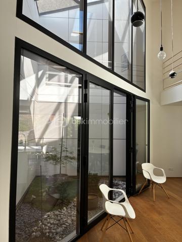 Confidentielle, contemporaine et résolument singulière.

À l’abri des regards, derrière une discrète porte cochère, se dévoile une maison d’architecte de 151 m², nichée au cœur de l’un des secteurs les plus recherchés de Tours, dans le très prisé quartier des Prébendes.
À quelques pas de l’hypercentre, cette adresse rare conjugue avec élégance intimité, architecture contemporaine et proximité immédiate de la vie tourangelle.

Dès l’entrée, la générosité des volumes et la hauteur sous plafond révèlent une conception pensée autour de la lumière et de la fluidité. La maison s’articule autour d’un remarquable patio végétalisé, véritable cœur architectural du lieu.

Le vaste séjour constitue la pièce maîtresse de la maison. Baigné de lumière naturelle par une élégante verrière et de larges baies vitrées, il offre une sensation remarquable d’espace et d’ouverture sur la végétation. La cuisine, parfaitement intégrée, prolonge cet ensemble dans une esthétique sobre et contemporaine.

Un salon plus intime vient compléter cet espace de réception, créant une atmosphère chaleureuse et raffinée.

Ici, chaque détail a été pensé dans un souci de confort et de discrétion. La maison bénéficie notamment d’un système audio Sonos intégré dans chaque pièce, permettant de prolonger l’expérience sonore dans l’ensemble de la propriété.

À l’étage, l’architecture se poursuit avec la même exigence. L’escalier ouvert préserve les perspectives et accompagne une belle mezzanine surplombant le séjour. Depuis celle-ci, les vues traversantes sur le patio et le jardin renforcent cette sensation de continuité entre intérieur et extérieur.
La chambre dispose d’un dressing aménagé et profite d’un environnement particulièrement préservé. Une élégante salle de bains complète cet étage avec douche, baignoire et WC.

À l’extérieur, le jardin paysager se découvre comme un prolongement naturel de la maison. Une sélection d’essences végétales compose un écrin intime et apaisant, tandis que la terrasse en bois invite aux longues soirées d’été et aux moments de convivialité.
L’adresse réserve enfin un privilège particulièrement recherché aux Prébendes : un porche couvert permettant le stationnement de deux véhicules.

UNE ADRESSE. UNE ARCHITECTURE. UNE ATMOSPHÈRE.

Plus qu’une maison, cette propriété offre une véritable expérience de vie : celle d’un lieu confidentiel où la lumière, la végétation et les volumes dialoguent en permanence.
Une architecture contemporaine d’exception, au caractère affirmé, dans l’un des quartiers les plus emblématiques de Tours.
Un bien rare, destiné aux amateurs d’architecture, de discrétion et d’adresses privilégiées.

Points forts : 
-Faible consommation d'énergie
-Une mezzanine pouvant faire office de chambre supplémentaire 
-Cuisine tout équipée 
-La maison peut être vendue meublée