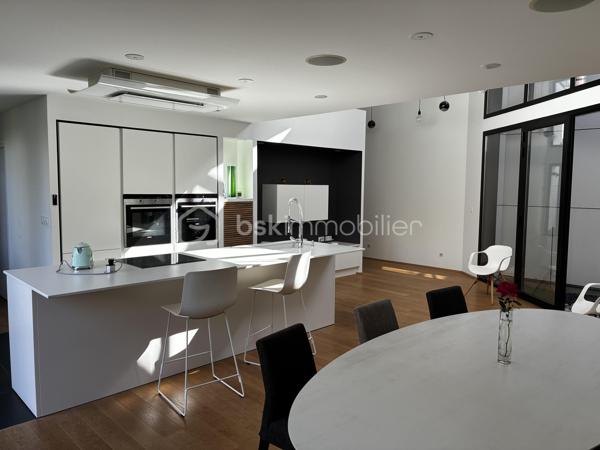 Confidentielle, contemporaine et résolument singulière.

À l’abri des regards, derrière une discrète porte cochère, se dévoile une maison d’architecte de 151 m², nichée au cœur de l’un des secteurs les plus recherchés de Tours, dans le très prisé quartier des Prébendes.
À quelques pas de l’hypercentre, cette adresse rare conjugue avec élégance intimité, architecture contemporaine et proximité immédiate de la vie tourangelle.

Dès l’entrée, la générosité des volumes et la hauteur sous plafond révèlent une conception pensée autour de la lumière et de la fluidité. La maison s’articule autour d’un remarquable patio végétalisé, véritable cœur architectural du lieu.

Le vaste séjour constitue la pièce maîtresse de la maison. Baigné de lumière naturelle par une élégante verrière et de larges baies vitrées, il offre une sensation remarquable d’espace et d’ouverture sur la végétation. La cuisine, parfaitement intégrée, prolonge cet ensemble dans une esthétique sobre et contemporaine.

Un salon plus intime vient compléter cet espace de réception, créant une atmosphère chaleureuse et raffinée.

Ici, chaque détail a été pensé dans un souci de confort et de discrétion. La maison bénéficie notamment d’un système audio Sonos intégré dans chaque pièce, permettant de prolonger l’expérience sonore dans l’ensemble de la propriété.

À l’étage, l’architecture se poursuit avec la même exigence. L’escalier ouvert préserve les perspectives et accompagne une belle mezzanine surplombant le séjour. Depuis celle-ci, les vues traversantes sur le patio et le jardin renforcent cette sensation de continuité entre intérieur et extérieur.
La chambre dispose d’un dressing aménagé et profite d’un environnement particulièrement préservé. Une élégante salle de bains complète cet étage avec douche, baignoire et WC.

À l’extérieur, le jardin paysager se découvre comme un prolongement naturel de la maison. Une sélection d’essences végétales compose un écrin intime et apaisant, tandis que la terrasse en bois invite aux longues soirées d’été et aux moments de convivialité.
L’adresse réserve enfin un privilège particulièrement recherché aux Prébendes : un porche couvert permettant le stationnement de deux véhicules.

UNE ADRESSE. UNE ARCHITECTURE. UNE ATMOSPHÈRE.

Plus qu’une maison, cette propriété offre une véritable expérience de vie : celle d’un lieu confidentiel où la lumière, la végétation et les volumes dialoguent en permanence.
Une architecture contemporaine d’exception, au caractère affirmé, dans l’un des quartiers les plus emblématiques de Tours.
Un bien rare, destiné aux amateurs d’architecture, de discrétion et d’adresses privilégiées.

Points forts : 
-Faible consommation d'énergie
-Une mezzanine pouvant faire office de chambre supplémentaire 
-Cuisine tout équipée 
-La maison peut être vendue meublée